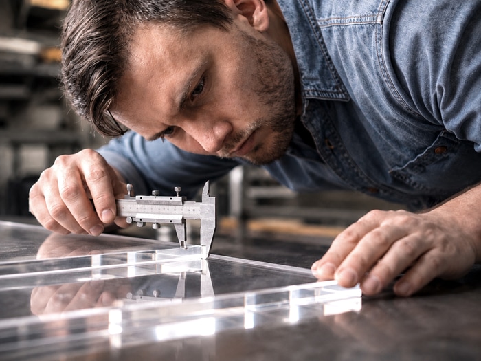 Contrôle au pied à coulisse d'une plaque de Plexiglass découpée sur mesure en atelier